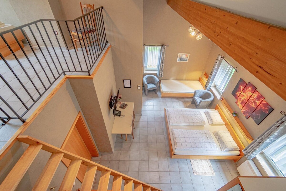 A multi-level room with a staircase, a bed, a desk, and a chair.