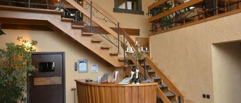 A spacious lobby with a wooden reception desk, a staircase, and a door.