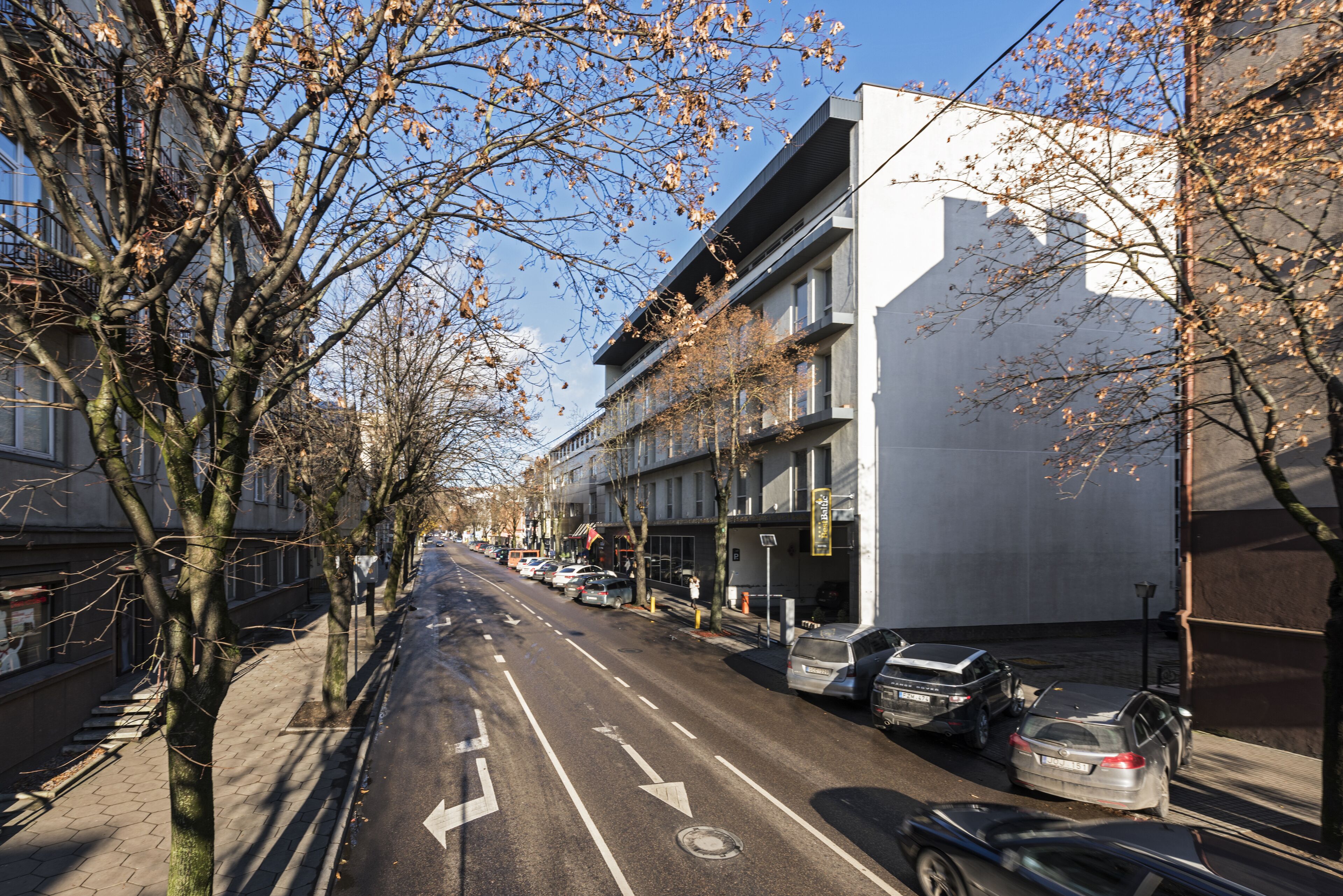 Una calle con coches aparcados, árboles y edificios.