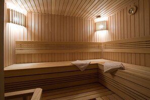 Una sauna con bancos de madera y paredes de listones, equipada con luces fijadas a la pared.