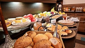 Een buffet met verschillende broden, gebak, fruit en toevoegingen.