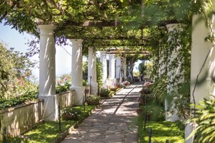 Ein Gartenpfad mit weißen Säulen und viel Grün.