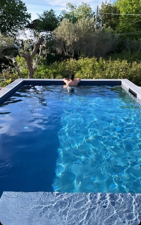 Una piscina al aire libre de temporada, sombrillas