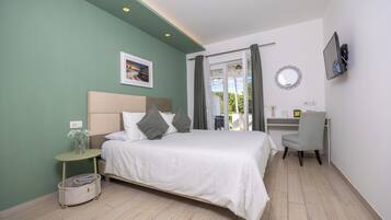 Un dormitorio con cama, mesita de noche, silla, escritorio y televisor.