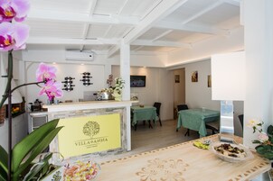 Eine Hotelhalle mit einer Rezeption, einem Essbereich und einem an der Wand befestigten Fernseher.