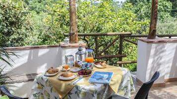 Een terras met een ontbijttafel, compleet met croissants, fruit en een drankje.