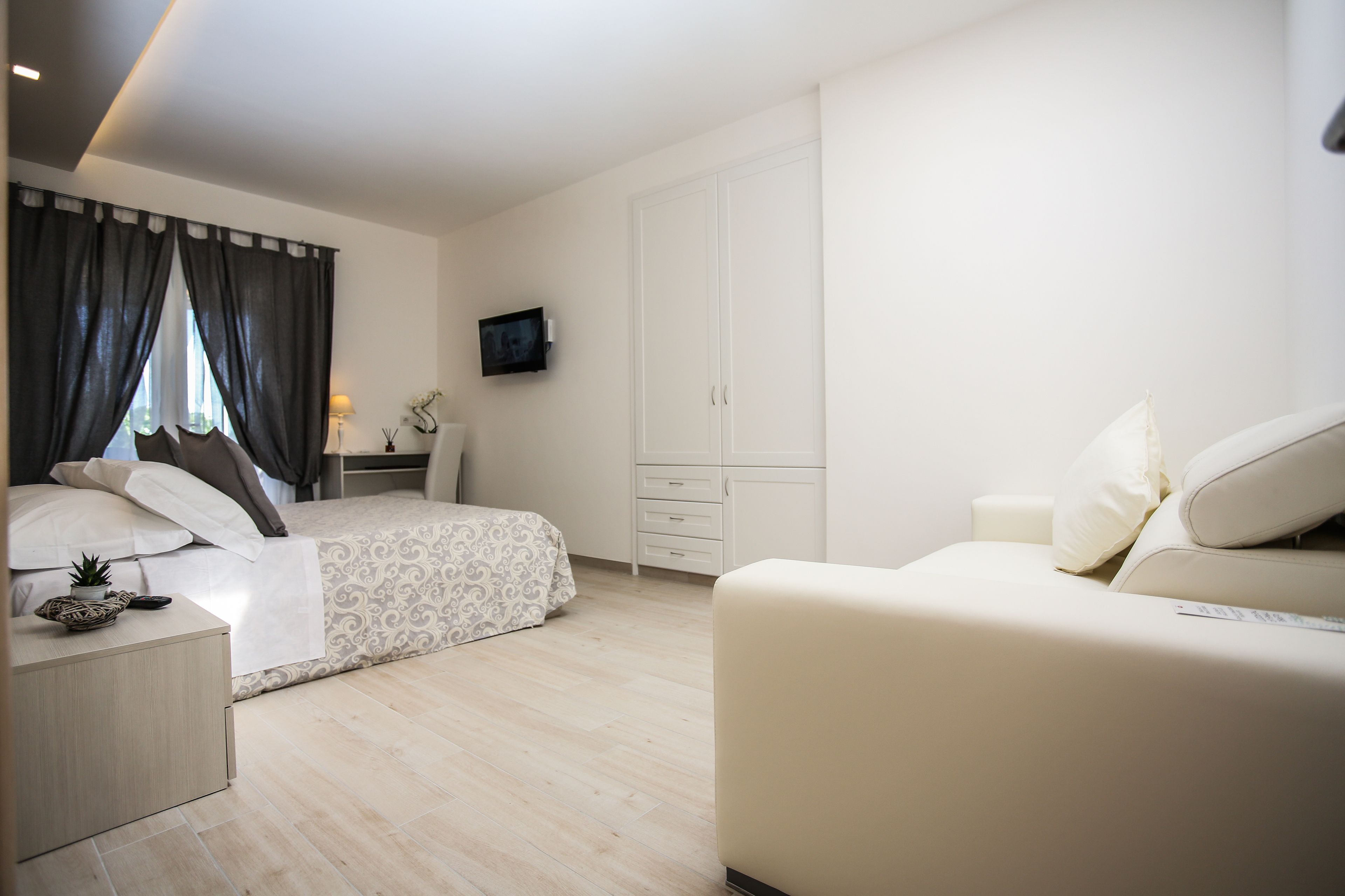 Ein modernes Schlafzimmer mit Bett, Nachttisch, Kommode und Fernseher.
