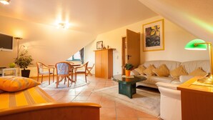 A cozy living room with a sofa, coffee table, and dining area. - Hotel Garni Schneevoigt (Hagenburg)
