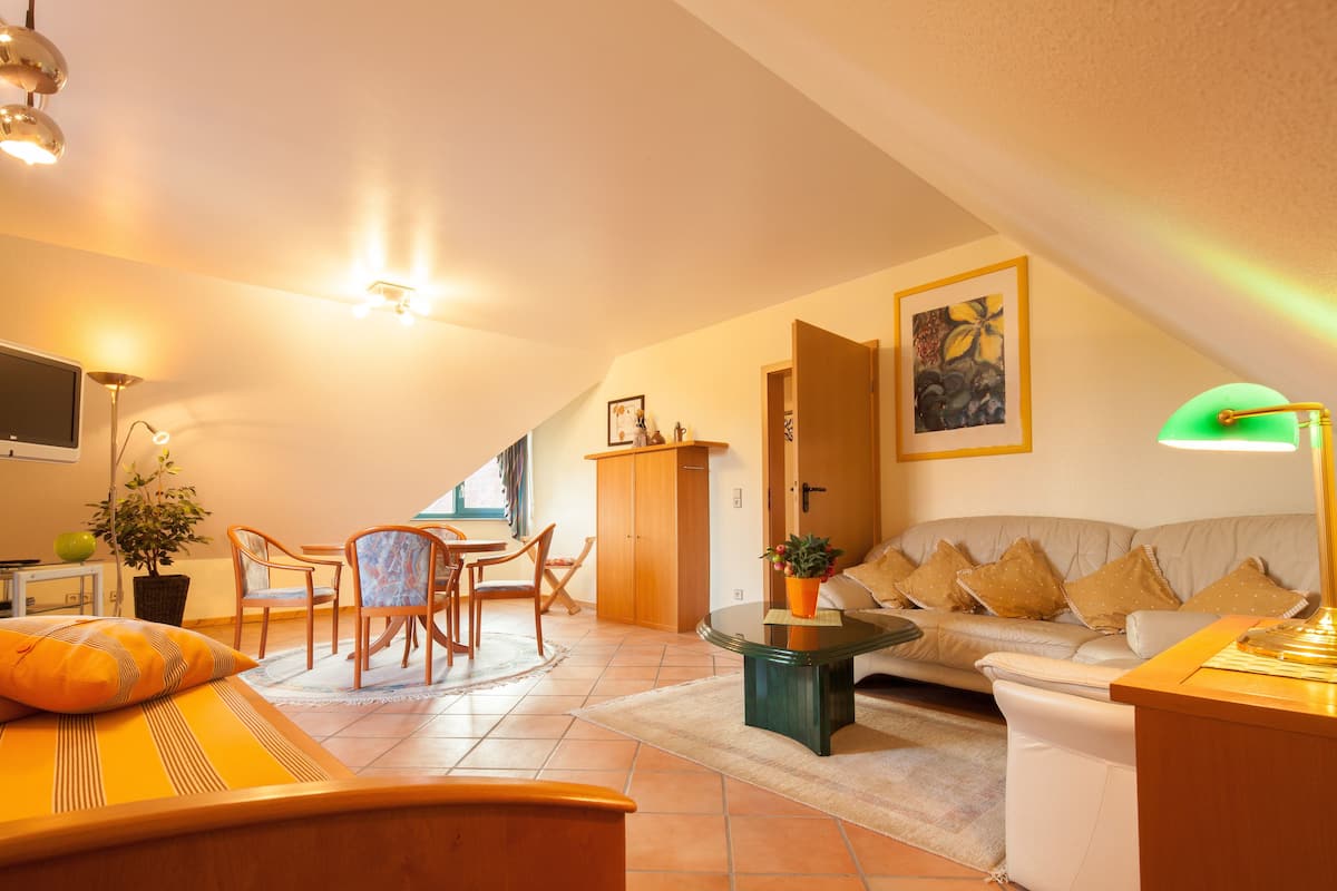 A cozy living room with a sofa, coffee table, and dining area.