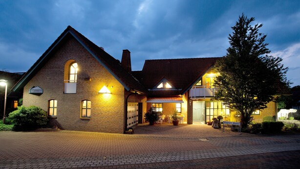 A brick building with a sloped roof, a garage door, and a sign that reads "Hotel." - Hotel Garni Schneevoigt (Hagenburg)