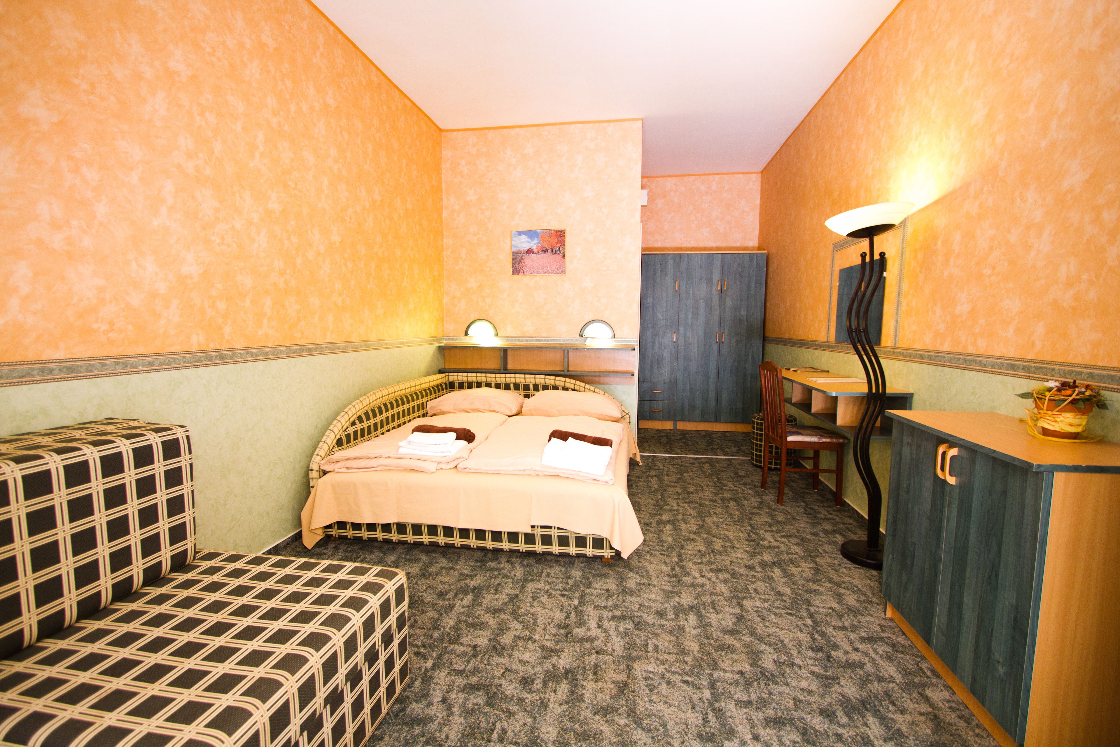 Een kleine, knusse kamer met een bed, een bureau en een stoel.