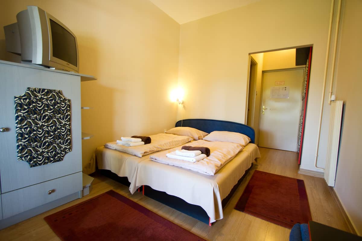 A hotel room with a bed, a desk, a television, and a wardrobe.