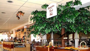 A cafeteria with a large artificial tree and signs indicating food sections. - Piknik Wellness Hotel (Siófok)