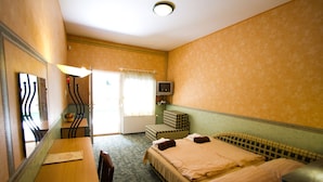 A hotel room with a bed, a desk, a chair, a television, and a window with curtains. - Piknik Wellness Hotel (Siófok)