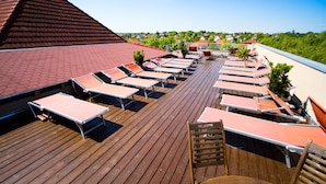 A rooftop deck with sun loungers and a red-tiled roof. - Piknik Wellness Hotel (Siófok)