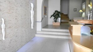 Un intérieur moderne avec un comptoir d’accueil, un escalier et une plante.