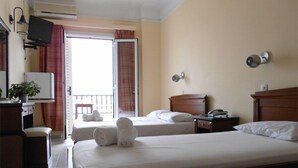 Une chambre d’hôtel avec deux lits, un bureau avec un ordinateur, une télévision et un balcon avec vue.