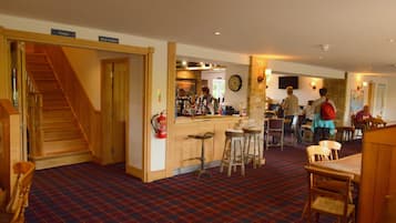 A hotel lobby with a bar area, a staircase, and a fire extinguisher.