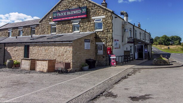 A stone building with a sign reading "Twice Brewed" and a small attached structure.