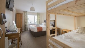 A room with bunk beds, a desk with a computer, and a window with curtains.