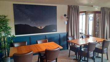 Un salón de conferencias con una gran mesa y sillas, un mural en la pared y una planta en maceta.
