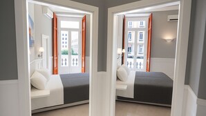 A mirrored room with a bed, bedside tables, and a view of buildings through a door. - Piazza Bovio 22 (Naples)