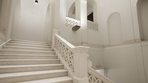 A marble staircase with intricate balustrades and white walls with decorative moldings. - Piazza Bovio 22 (Naples)