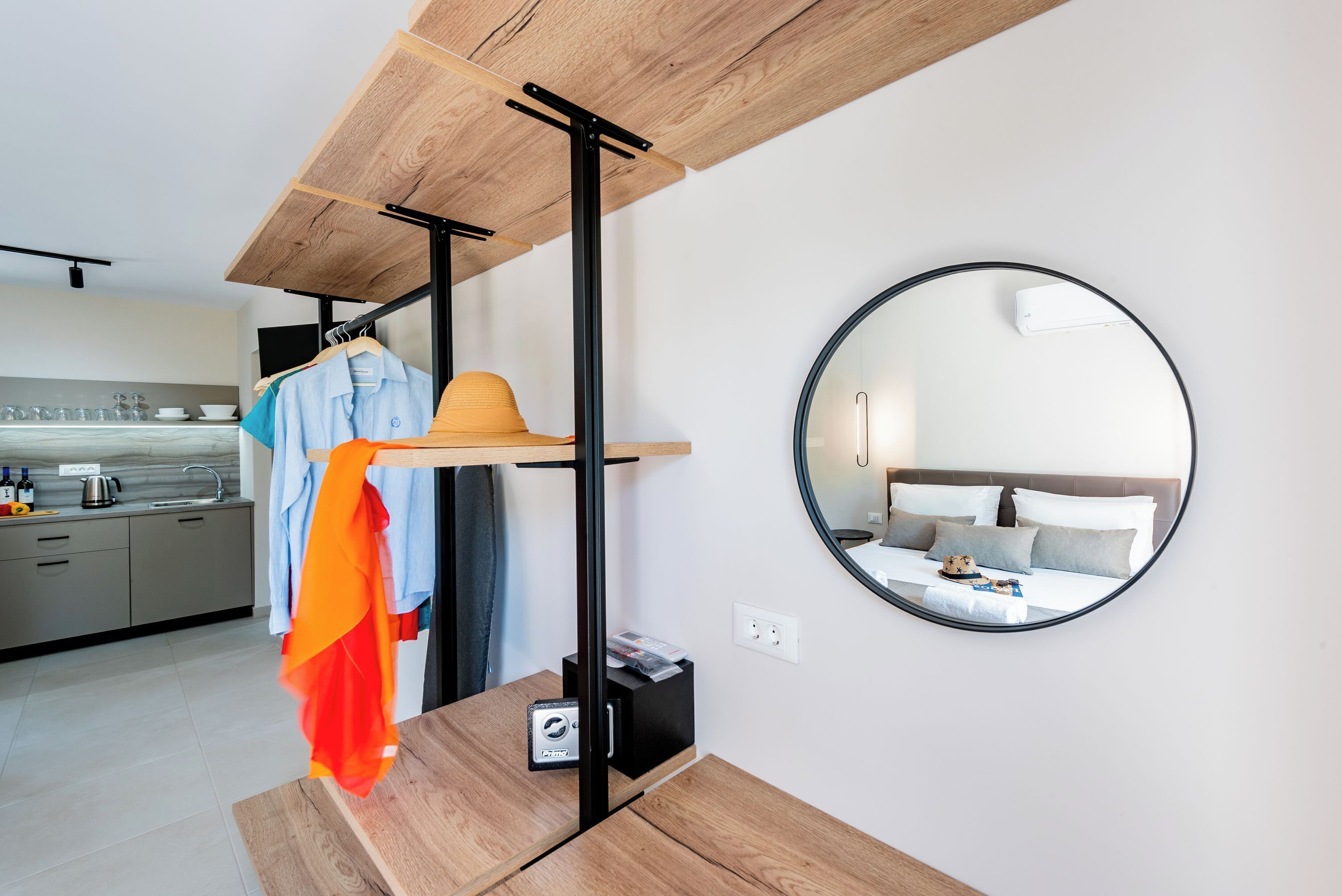 A modern hotel room with a wooden ceiling, a round mirror, a bed with pillows, and a small bedside table.