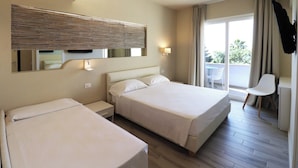 Ein Hotelzimmer mit zwei Betten, einem Balkon mit einem Stuhl und einem großen Spiegel über den Betten.