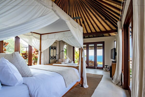 A bedroom with a large bed, a smaller bed, a TV, and a view of the ocean. - The Ungasan Clifftop Resort (Pecatu)