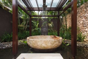 Een aparte badkuip en douche, een diep bad, een regendouche