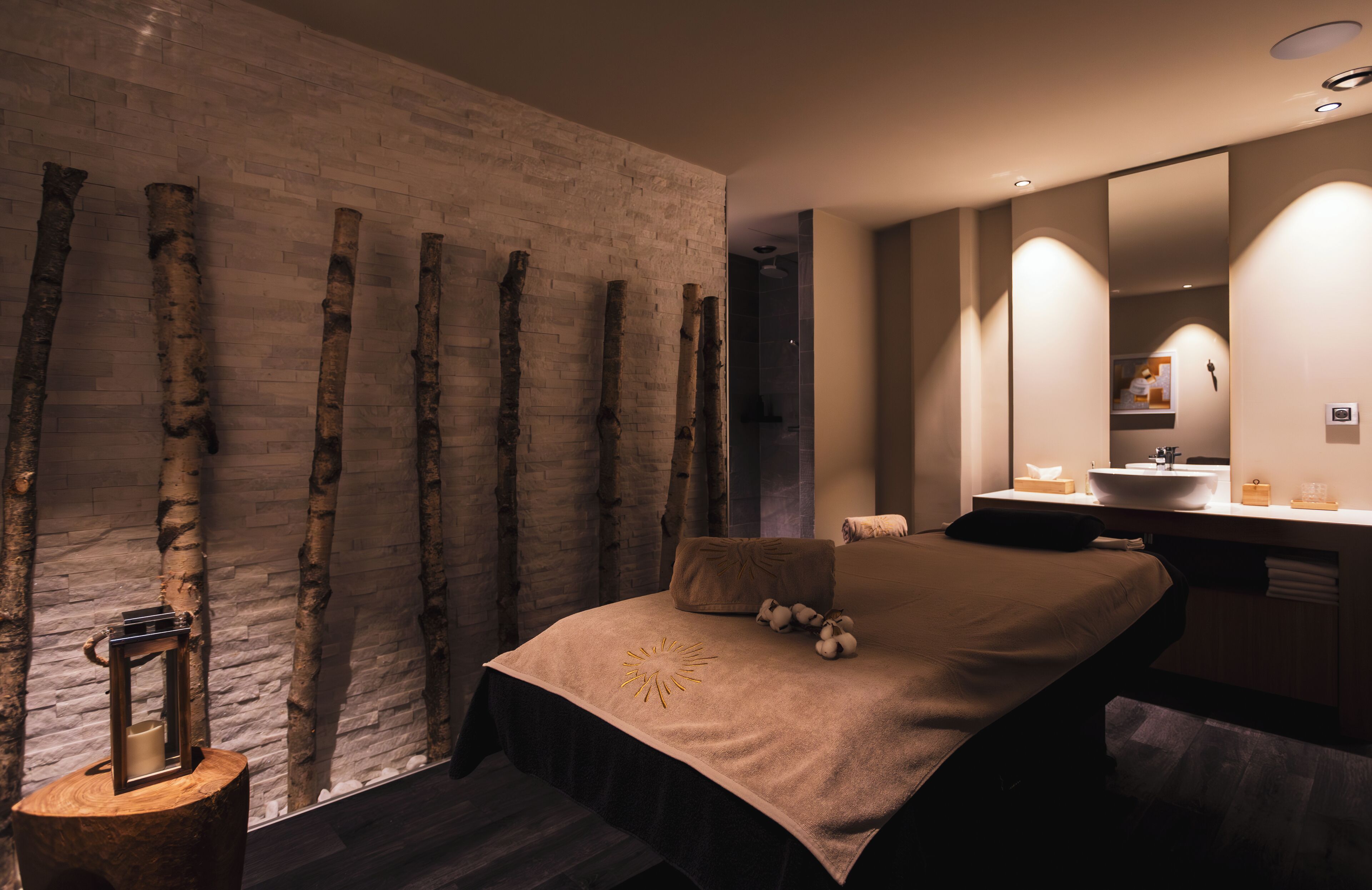 A modern bedroom with a large bed, a wooden wall, and a bathroom with a large mirror and sink.