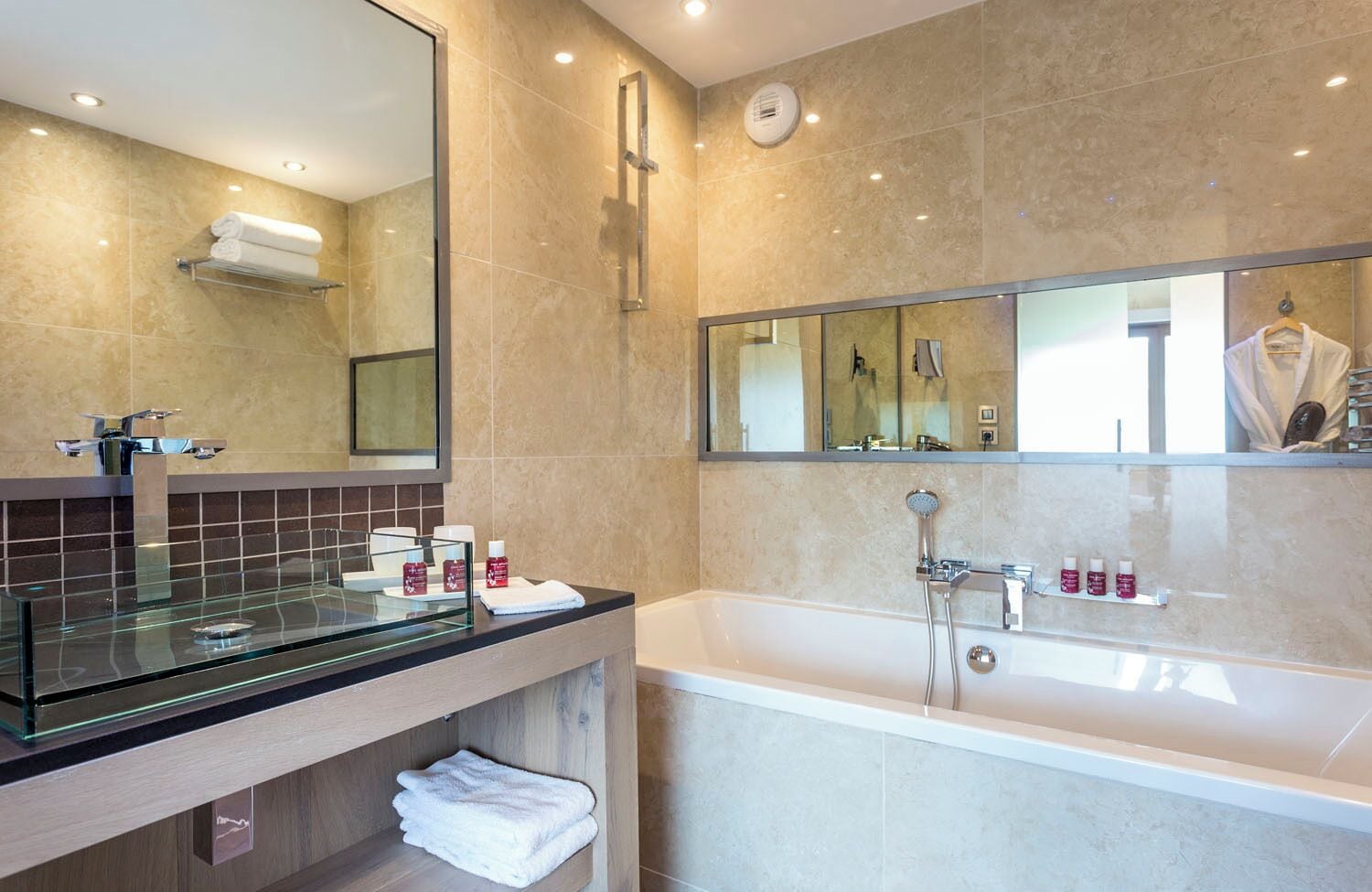 A modern bathroom with a glass shower enclosure, a large mirror, and a bathtub.