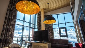 A modern living room with a large window, wooden ceiling, and a flat-screen TV. - Hôtel Taj-I Mah by Les Etincelles  (Bourg-Saint-Maurice)