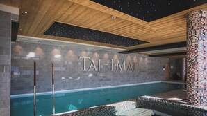 A modern indoor pool area with a starry ceiling, a large wall with the name "TAJ-IMAH" in large letters, and a mosaic-tiled column. - Hôtel Taj-I Mah by Les Etincelles  (Bourg-Saint-Maurice)