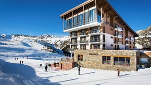 A multi-story hotel with a ski slope in the background. - Hôtel Taj-I Mah by Les Etincelles  (Bourg-Saint-Maurice)