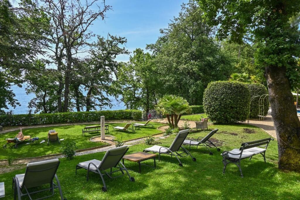 A garden with outdoor seating and a view of the sea.