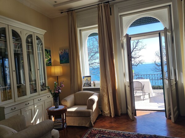 A room with a view of the sea, a fireplace, and a dining area.