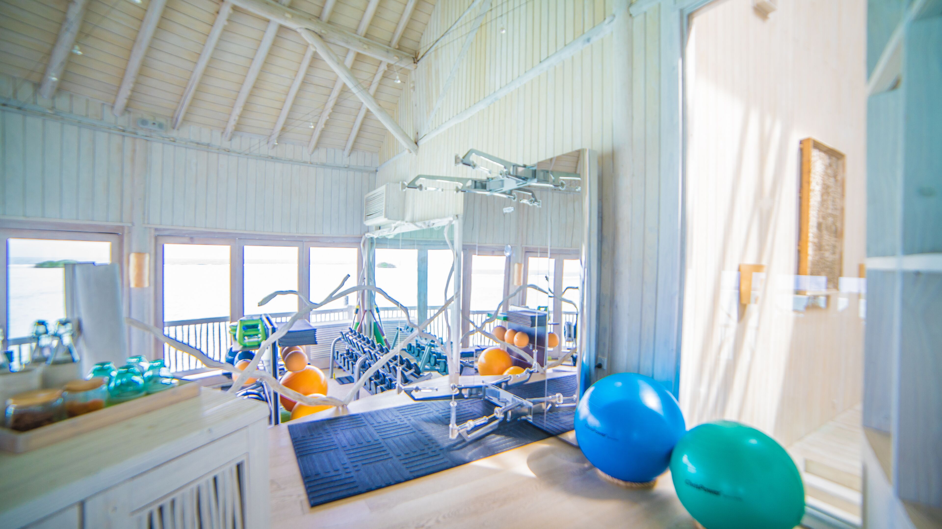 A gym with exercise equipment, a large window, and a view of the sea.