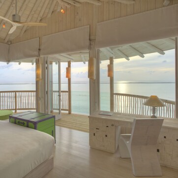 A room with a bed, a desk, and a view of the sea.