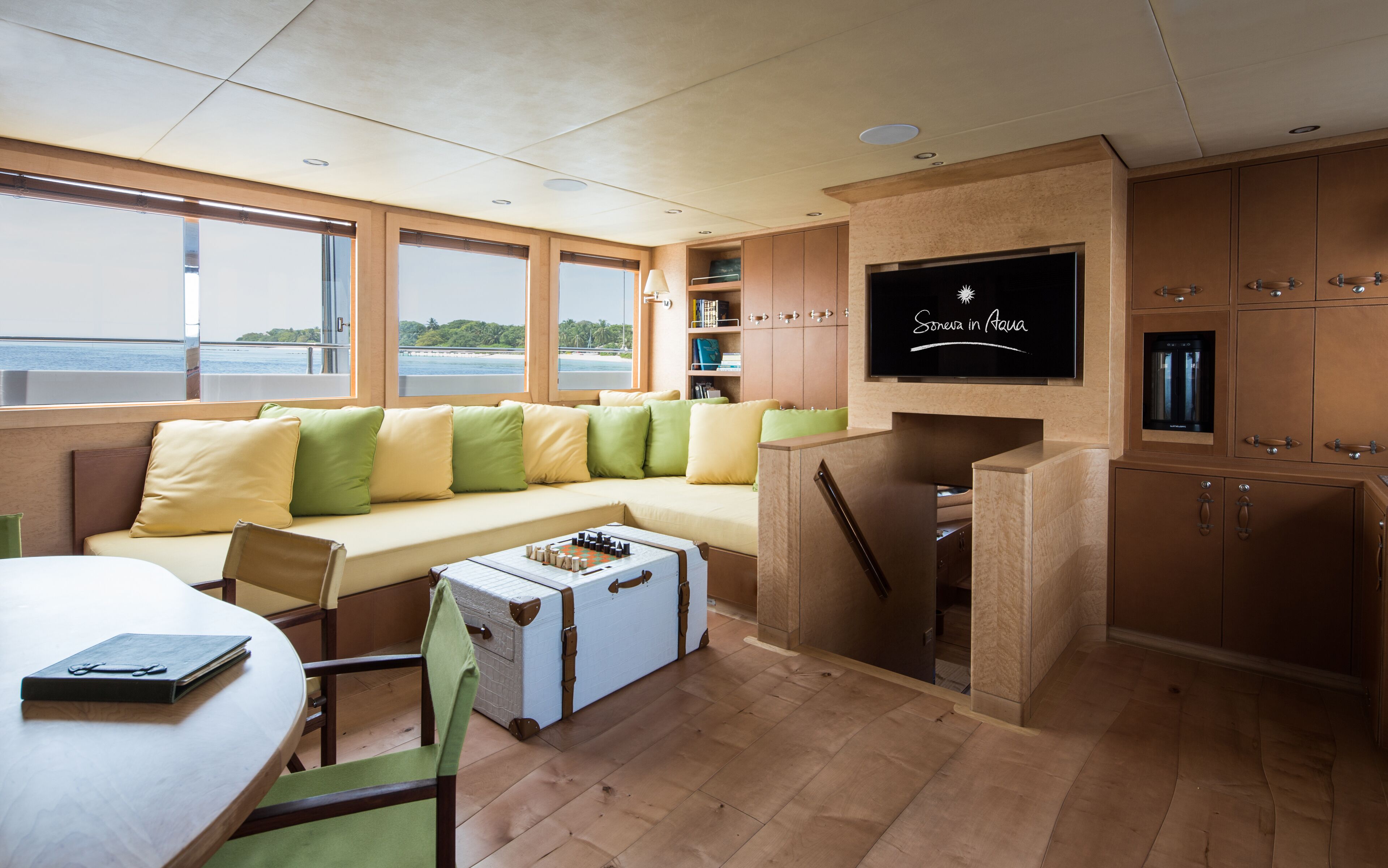 A compact, modern cabin with a sofa, a small dining table, and a TV mounted on the wall.