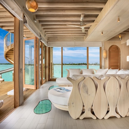 A modern interior with a wooden ceiling, large windows, and a view of the ocean.