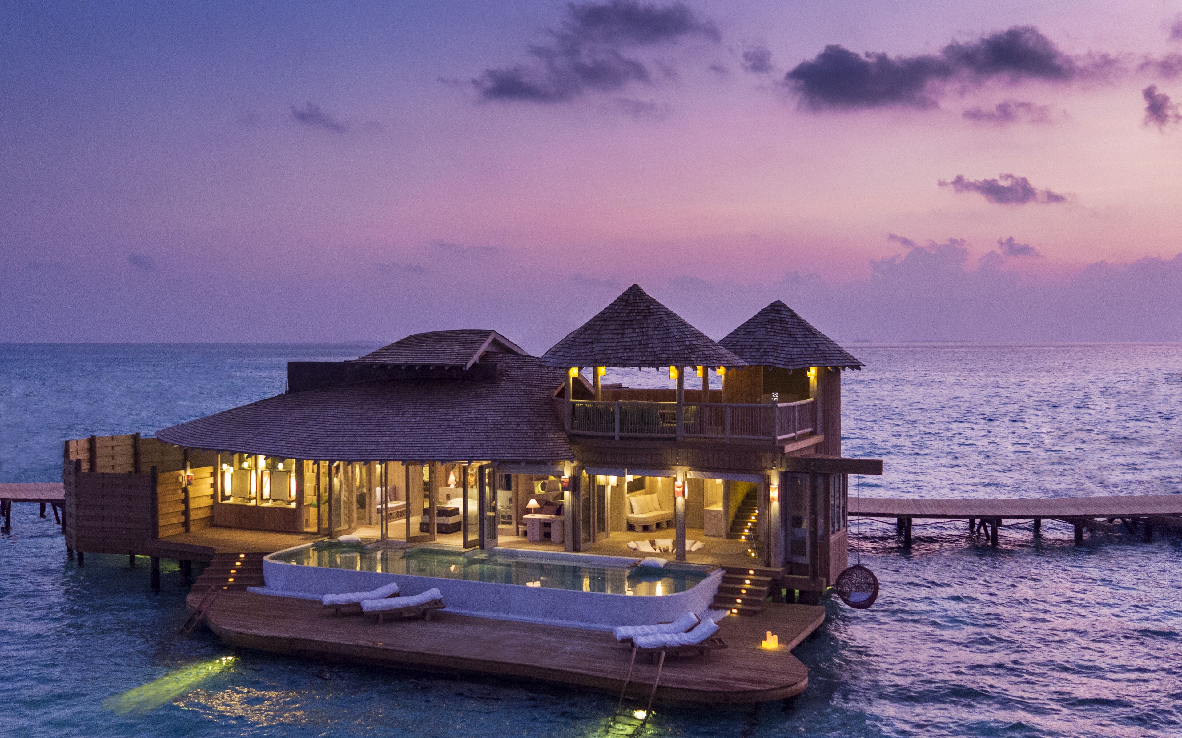 A luxurious overwater villa with a private pool, multiple levels, and a view of the ocean.