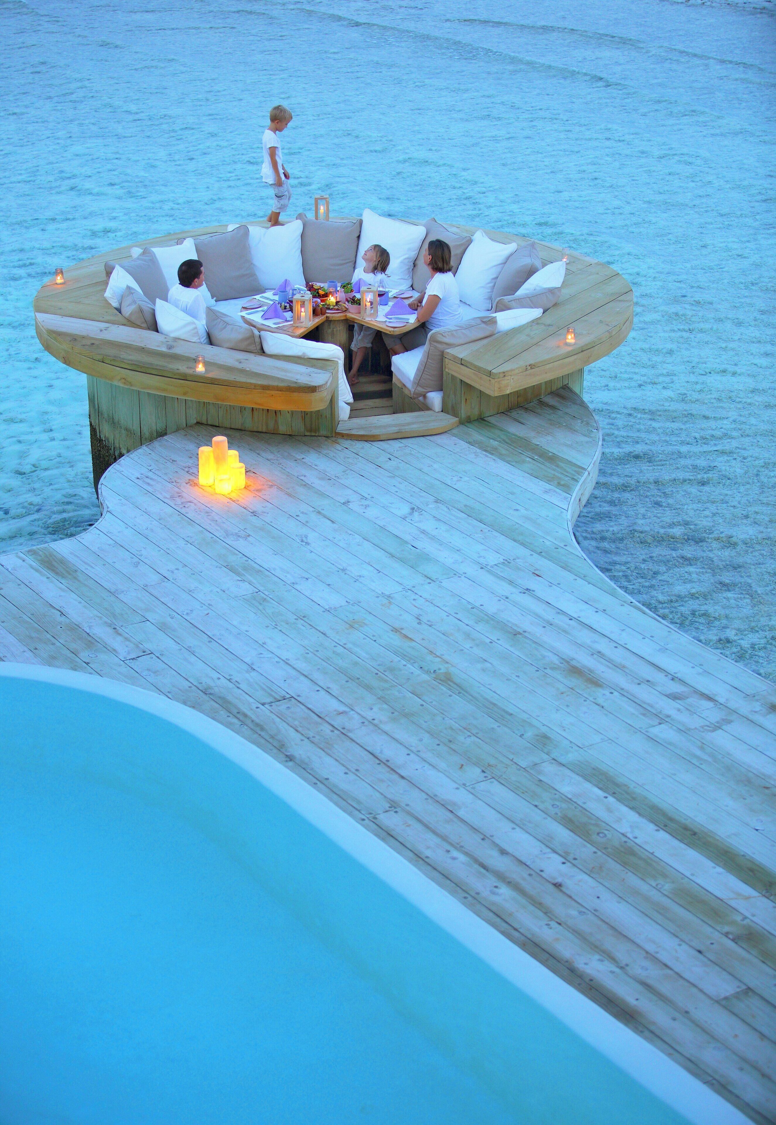A wooden deck with a built-in seating area overlooking a body of water.