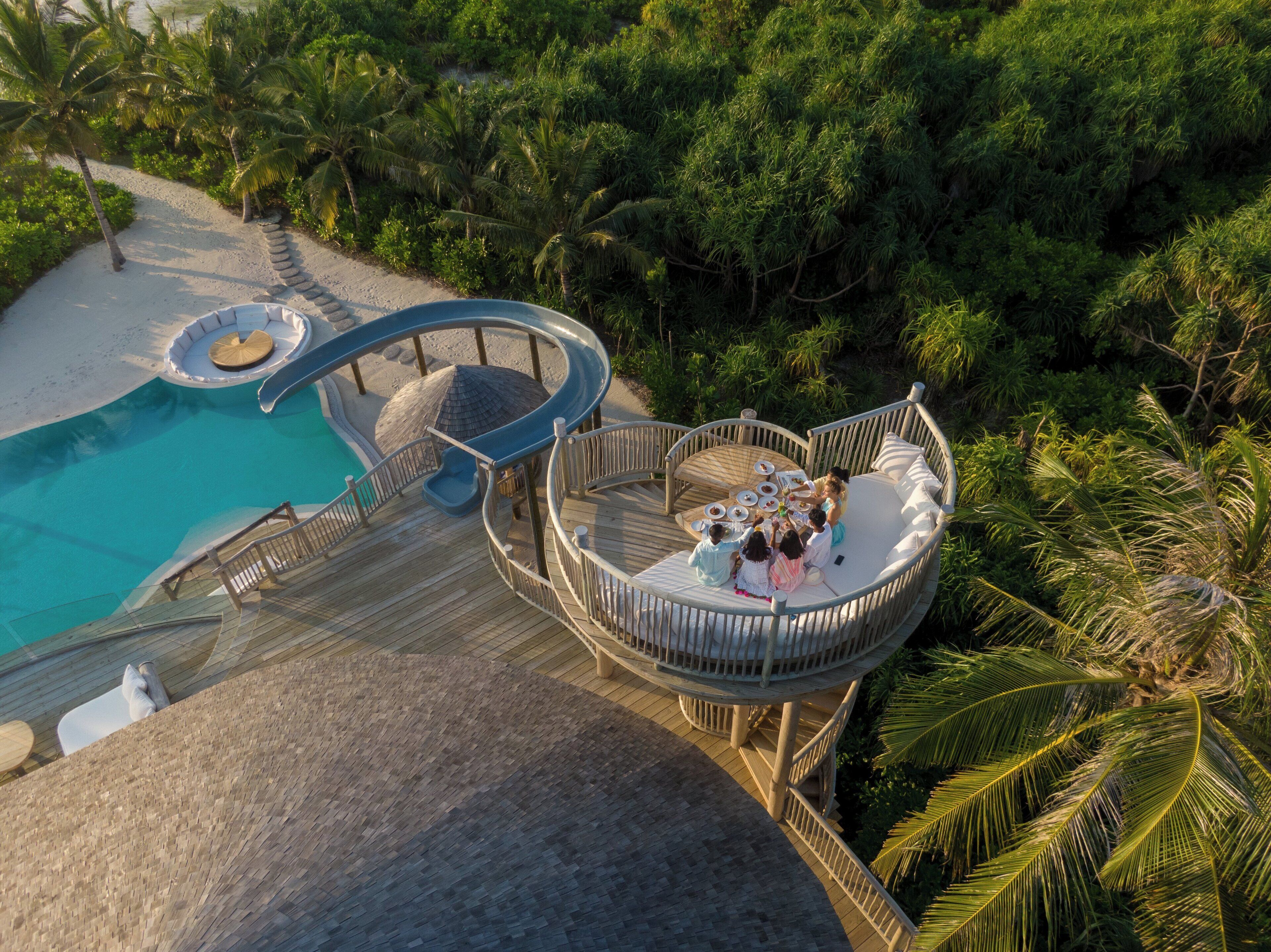 Un resort con piscina, terraza circular y palmeras.