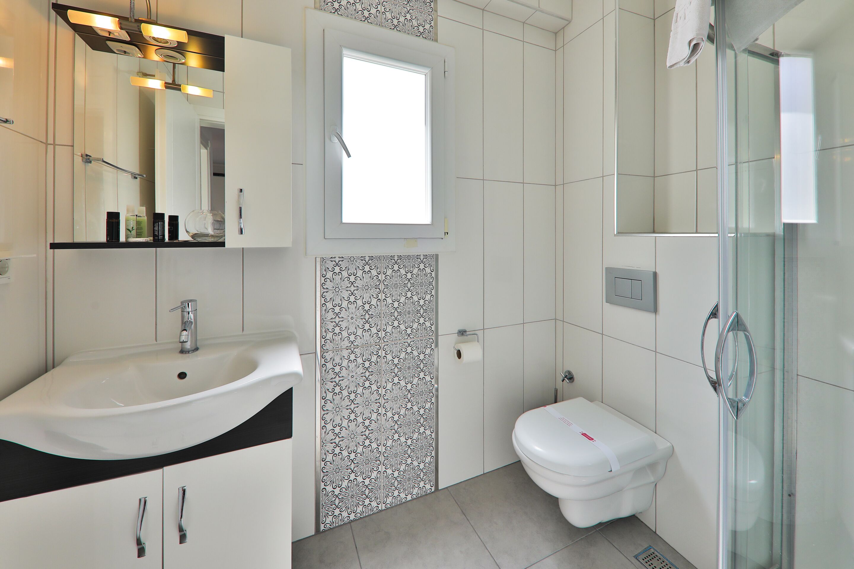 Un baño moderno con lavamanos blanco, inodoro y cabina de ducha de vidrio.