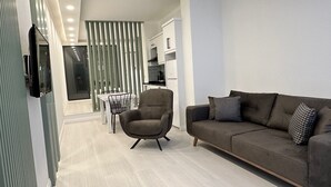 A modern living room with a sofa, a dining table, and a kitchen area in the background. - Bossa Nova Apart (Kas)