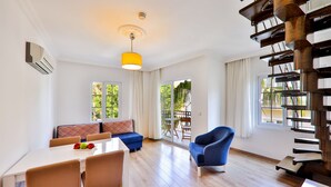 A spacious living area with a dining table, blue chairs, a sofa, and a staircase. - Bossa Nova Apart (Kas)