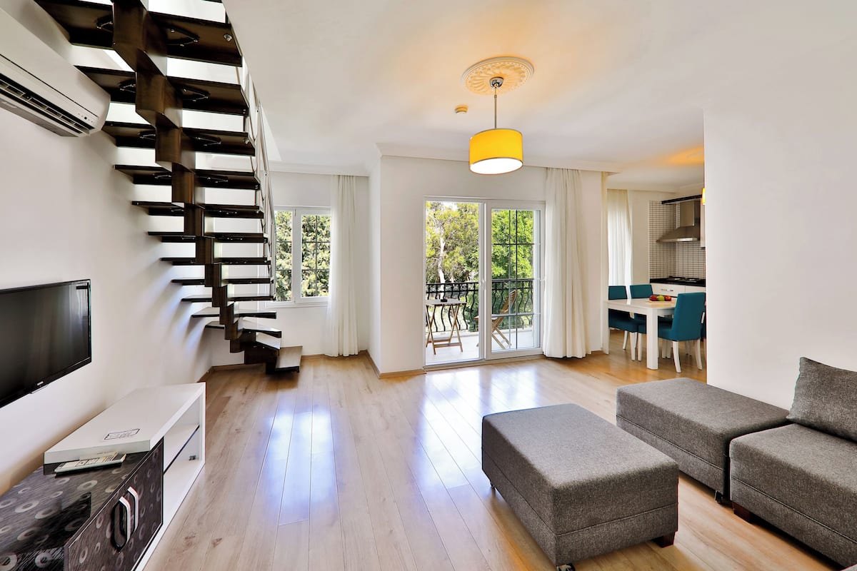 Una sala de estar moderna con una escalera, un comedor y una cocina.