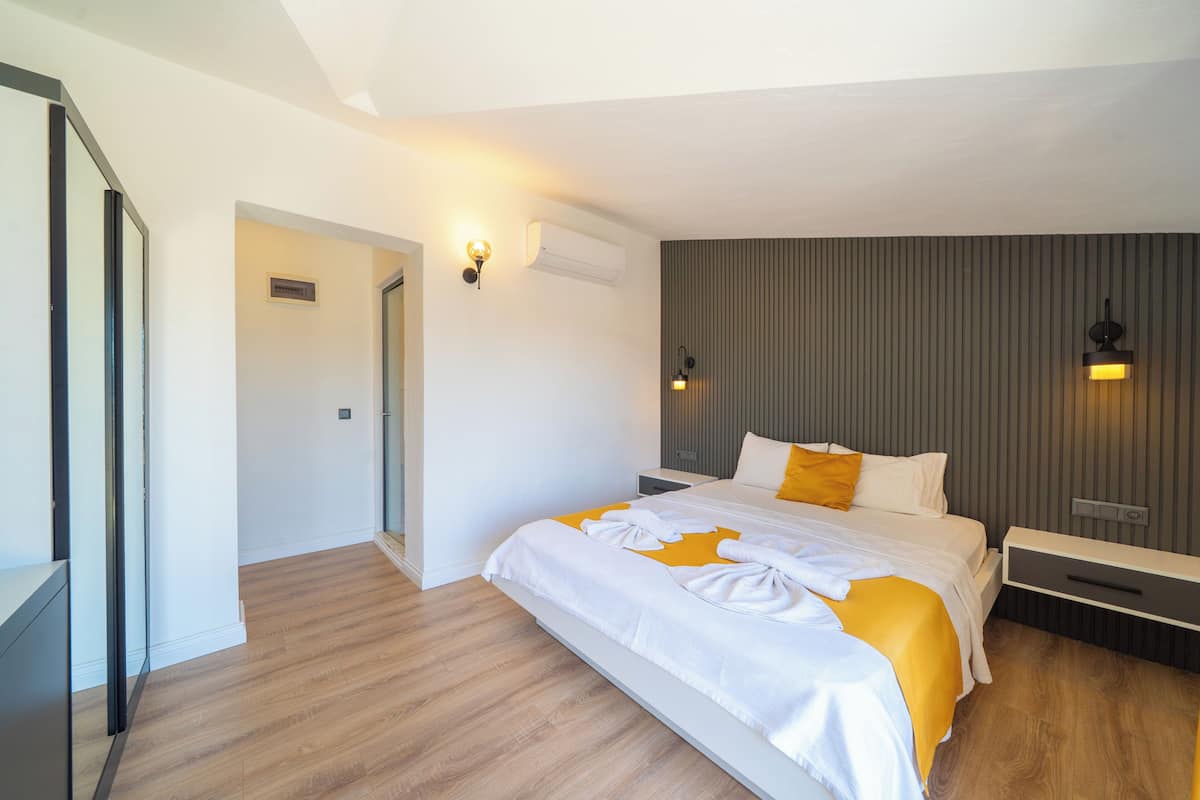 Una habitación de hotel moderna con una cama grande, mesitas de noche, un armario y un aire acondicionado instalado en la pared.